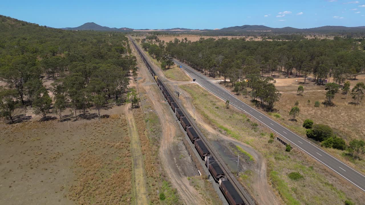 Forward moving aerial views over a coal train moving to words Gladstone, Central Queensland, Australia