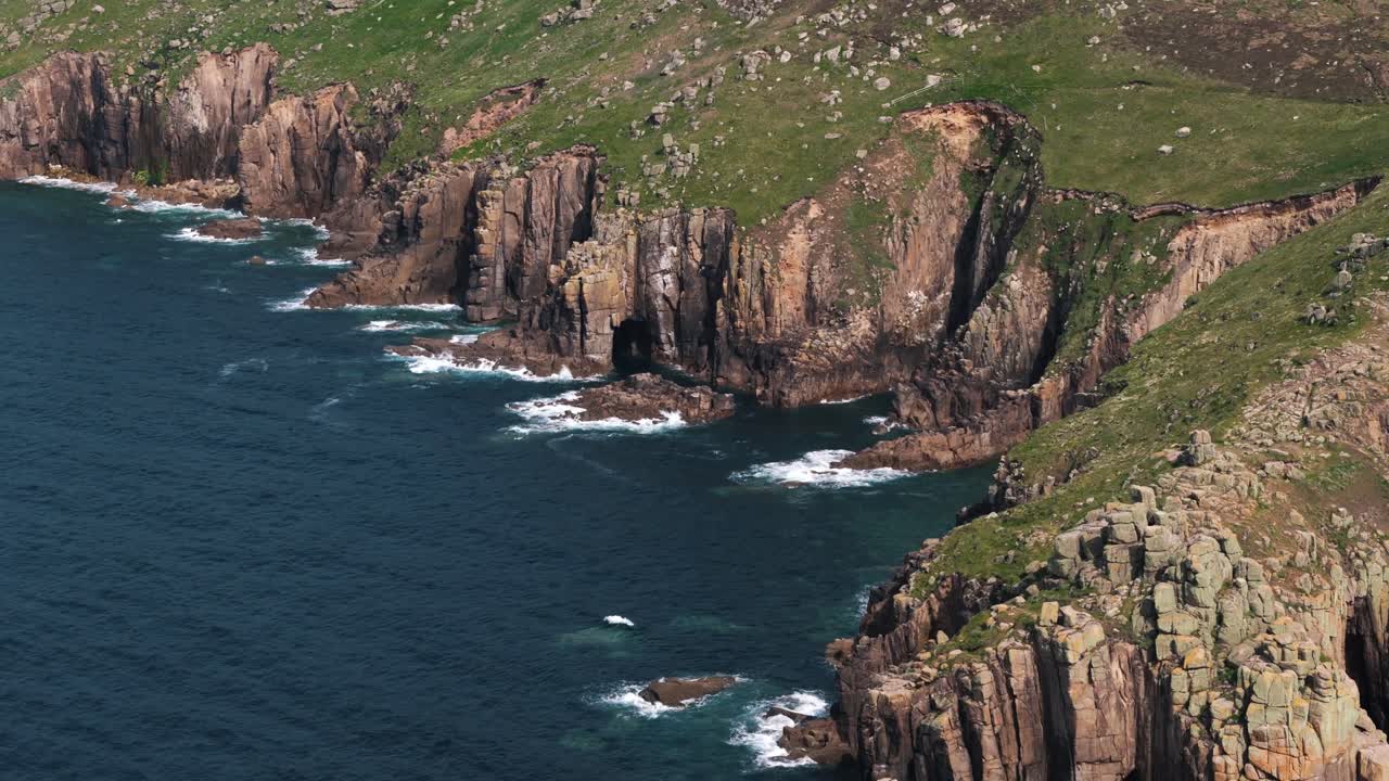 Descending pan up revealing Land’s End cliffs and deep blue water