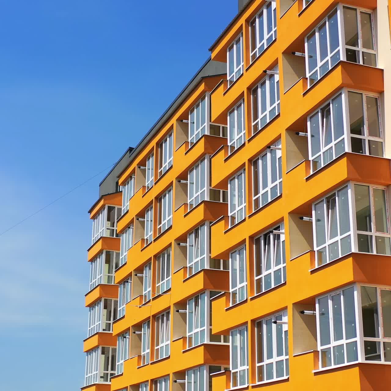 Block of flats with large balconies. Facade of a new high rise building on blue sky backdrop. Bright architecture in the city. Modern multi storey house