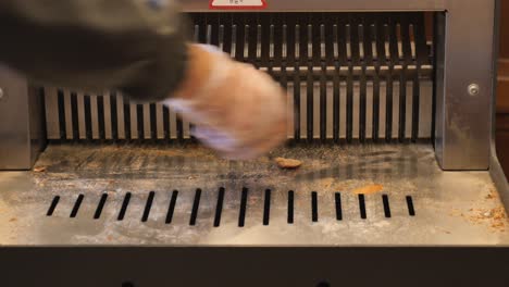 a baker uses a bread slicer to cut a fresh loaf of bread