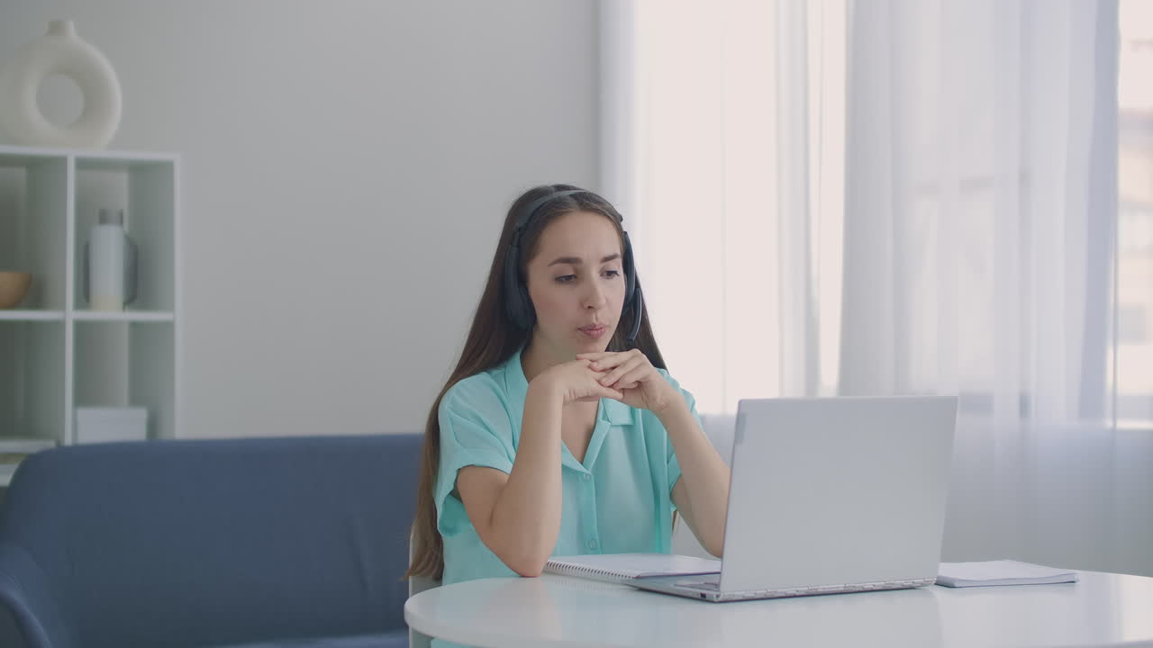 mujer estudiante sentarse en el escritorio en casa usar auriculares hablar a distancia por video llamada aplicación y dispositivo portátil e-aprender idiomas estudiar con e tutor o compañero de clase hacer tarea común remotamente concepto de tecnología moderna