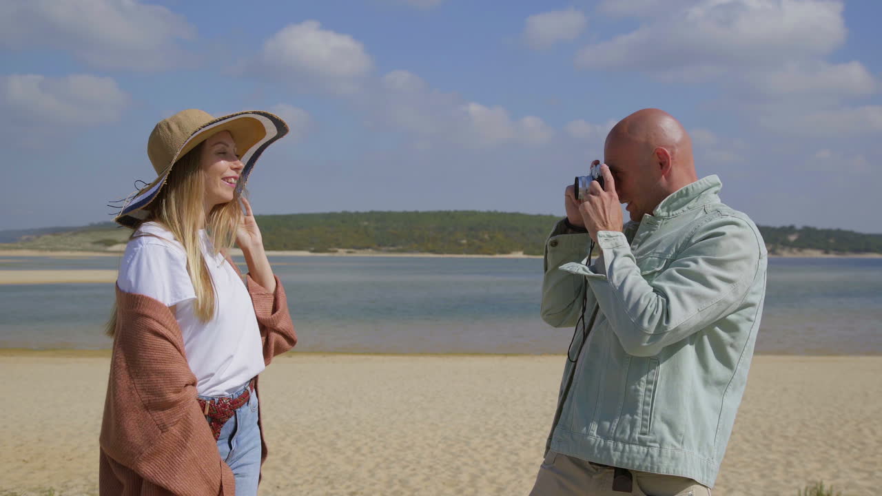 мужчина фотографирует красивую девушку на пляже.