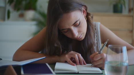 Mujer-Enfocada-Escribiendo-En-El-Escritorio-De-Casa