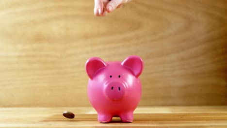 hand dropping coin into piggy bank