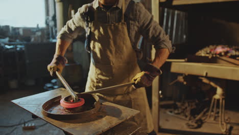 blacksmith bending hot metal rod into swirl form on anvil in workshop