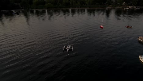 Veleros-Y-Catamarán-Flotando-En-El-Lago-Memphremagog-Cerca-De-Las-Casas-Frente-Al-Mar-En-Quebec,-Canadá