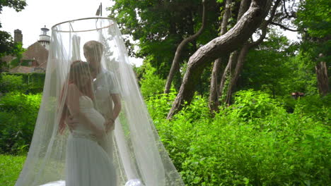 pregnant couple posing under under wedding canopy at park