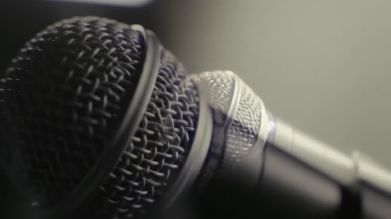 Close-Up Frames of a Microphone Capturing the Essence of Sound: An Intimate Look at the Instrument of Voice and Expression in a Dimly Lit Setting