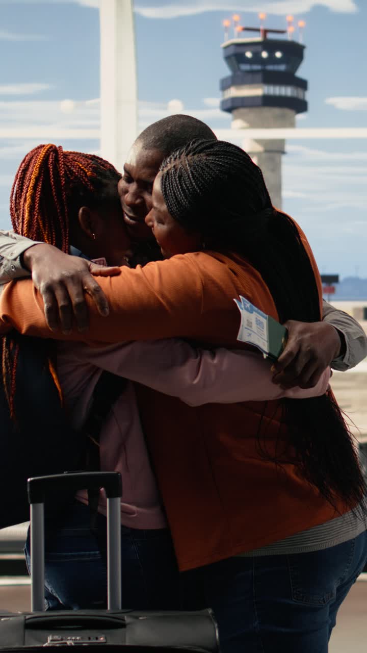 Video verticale: Scena emozionante di genitori afroamericani che abbracciano la figlia nel terminal dell'aeroporto.