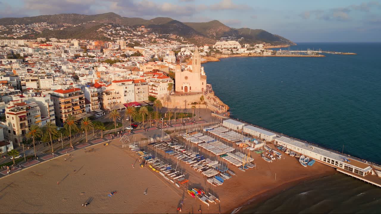 Luftfoto af kystbyen Sitges og strand ved den gyldne time.