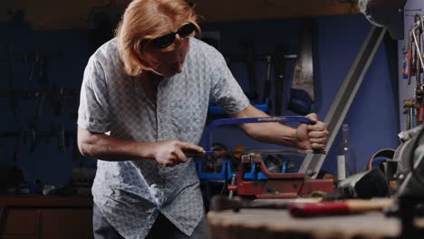 wide shot of mechanic cutting into the head of a bolt in his garage