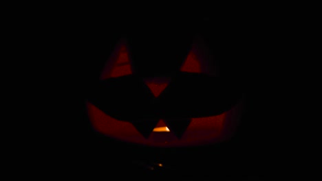 happy halloween 2 jack o' lanterns glowing in the dark wishing happy halloween: carved pumpkin decorations with burning candles inside.