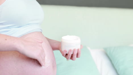 pregnant woman putting lotion on belly