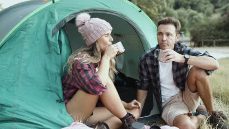 pareja de camping comiendo bocadillos, bebiendo té o café caliente