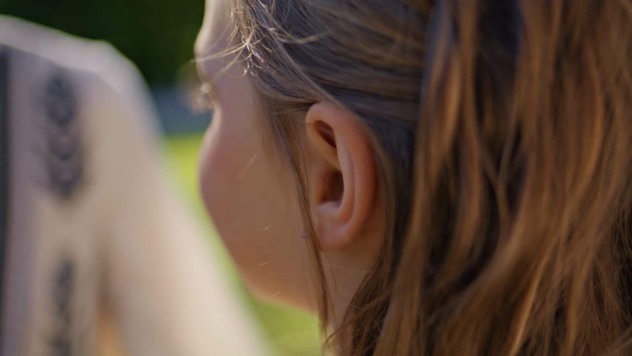 Mother hand touching daughter hair showing love tenderness on lawn grass closeup