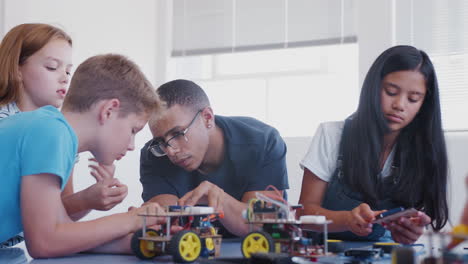 students with male teacher in after school computer coding class learning to program robot vehicle