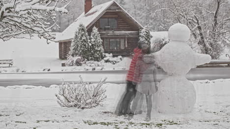 friends create a snowman in front of rural cottage. winter season, Christmas, friendship and enjoyment. Timelapse