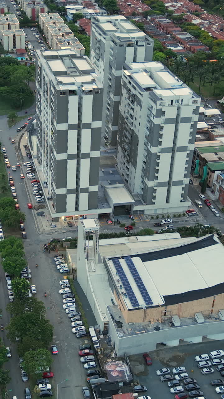 Stunning vertical video captures Valle del Lili's skyscrapers and bustling streets at dusk. The aerial footage showcases architectural grandeur with a serene, atmospheric glow
