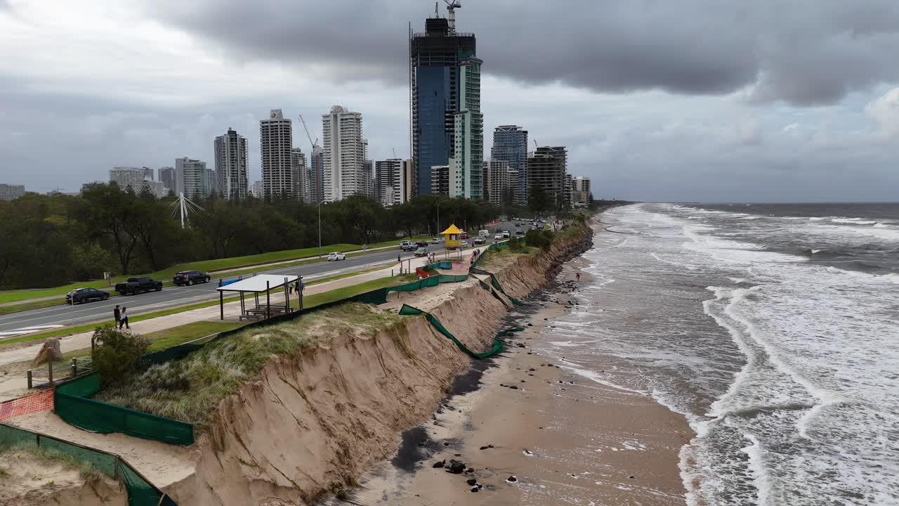 Aerial view of severe coastal erosion along Gold Coast, Australia, highlighting environmental impact and urban proximity under cloudy skies