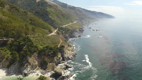 4k aerial: pan up reveals dramatic coastline in california's big sur with mcway falls waterfall in background