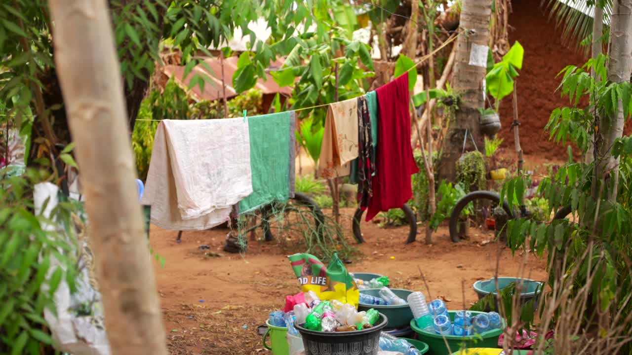 Freshly washed garments drying on washing line in lush greenery in rural African village