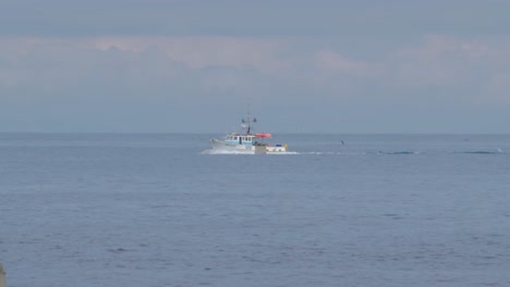 a racking shot of boat sailing behind a rock