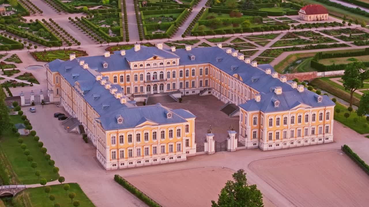 Evening drone shot of Rundale Palace surrounded by gardens and symmetry