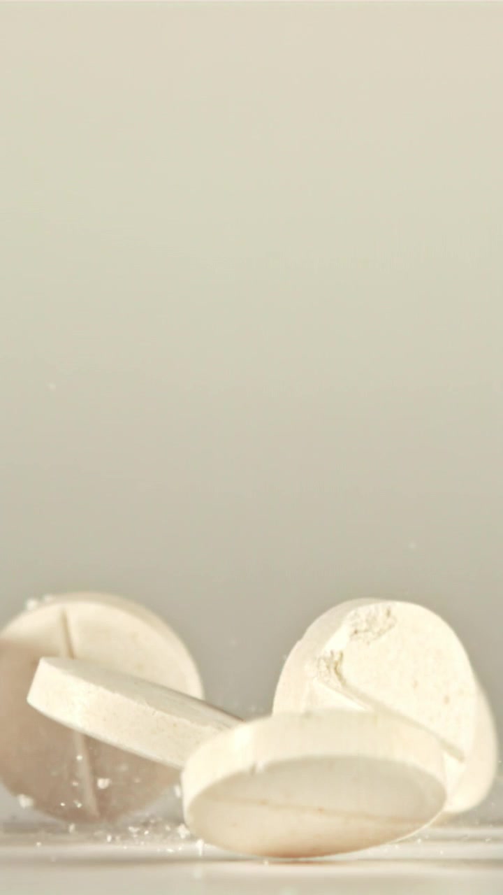 White Pills Falling and Breaking Apart in Slow Motion