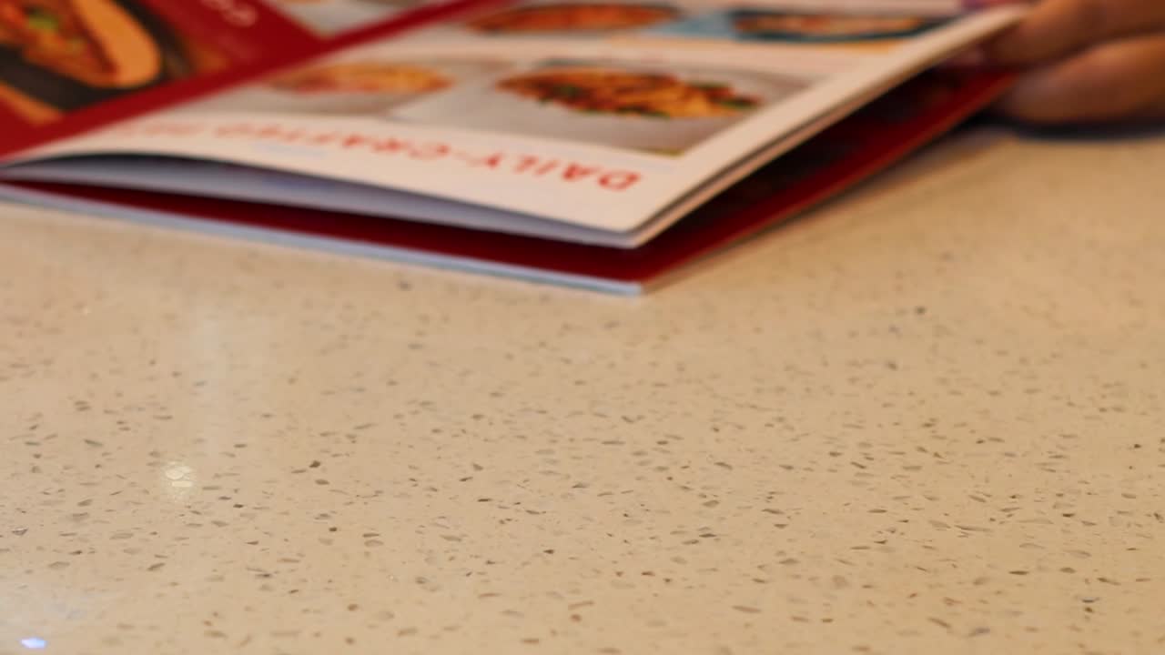 manos navegando por un menú en una mesa