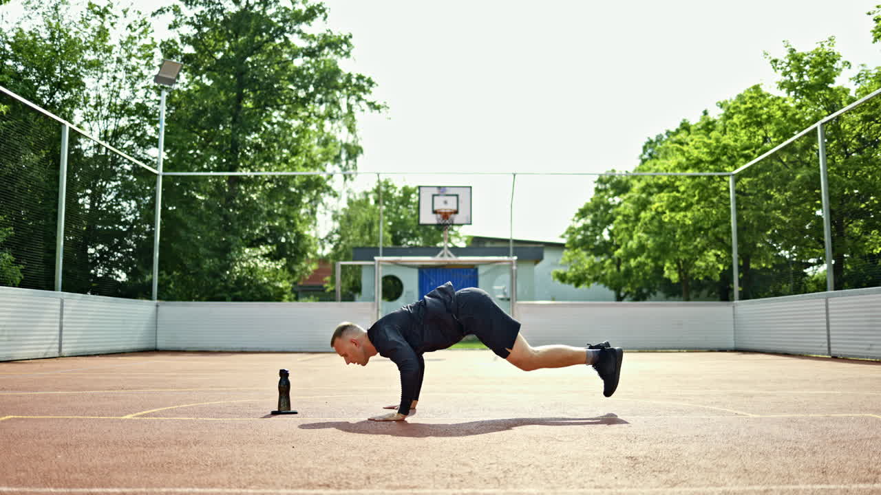 Un uomo sportivo in maglia e sneakers fa esercizi all'aperto. Un uomo fa sport su un parco giochi nel parco. Un uomo conduce uno stile di vita attivo. Un atleta fa esercizi all'aperto
