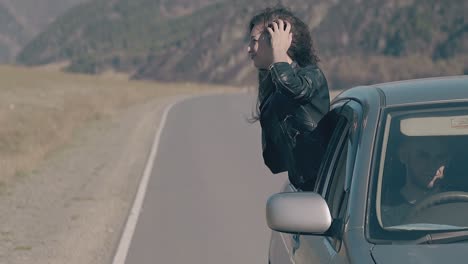 lady with long dark hair enjoys life leaning out of car