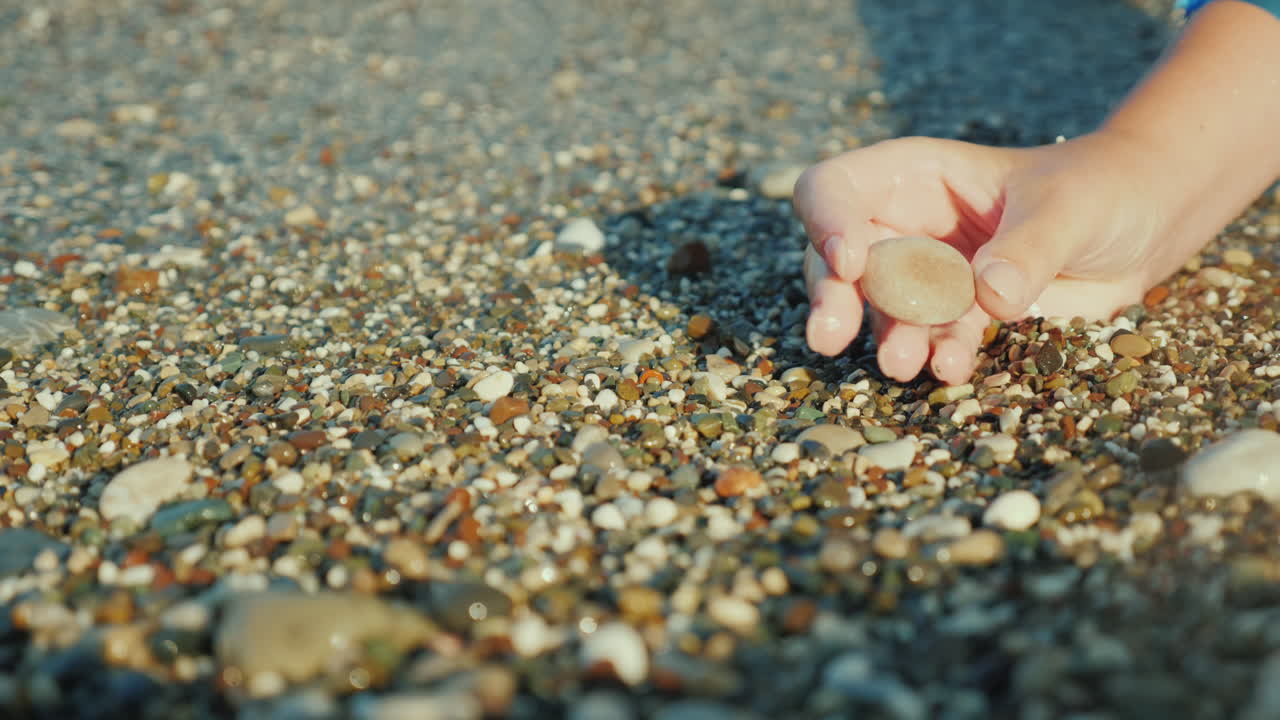 한 여자의 손이 서핑 4k 비디오의 배경에 조약돌을 들고 있다