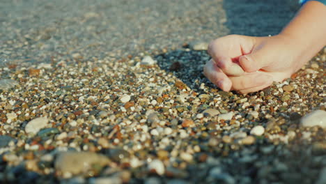 A-Woman's-Hand-Holds-A-Pebble-Against-The-Background-Of-The-Surf-4k-Video