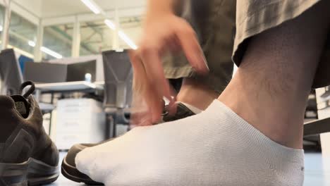 man takes off shoes and massages feet with white socks
