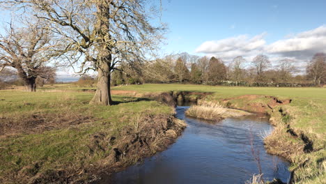 Bright-winter-sunshine-and-blue-sky-over-the-tiny-river-Arrow-and-the-Warwickshire-countryside,-England