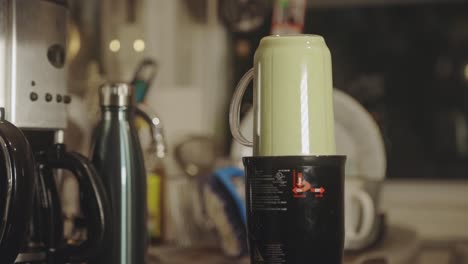 making nutritious green smoothie in a glass blender at the kitchen