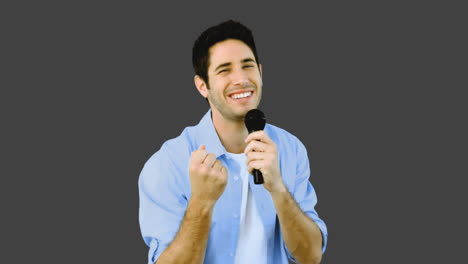 hombre cantando en el micrófono con emoción en fondo gris