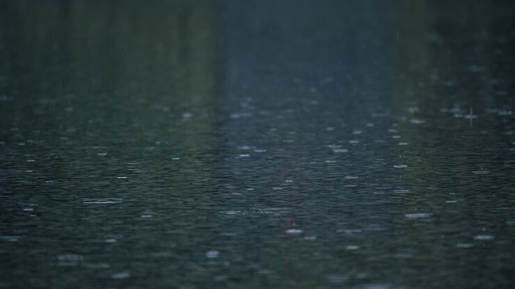 Slow motion of rain with splashes on wet asphalt surface