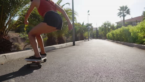 with palm trees in the backdrop, slow motion portrays a stunning young girl riding her longboard on the road by the beach