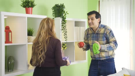 una pareja feliz y madura teniendo conversaciones divertidas limpiando su casa.