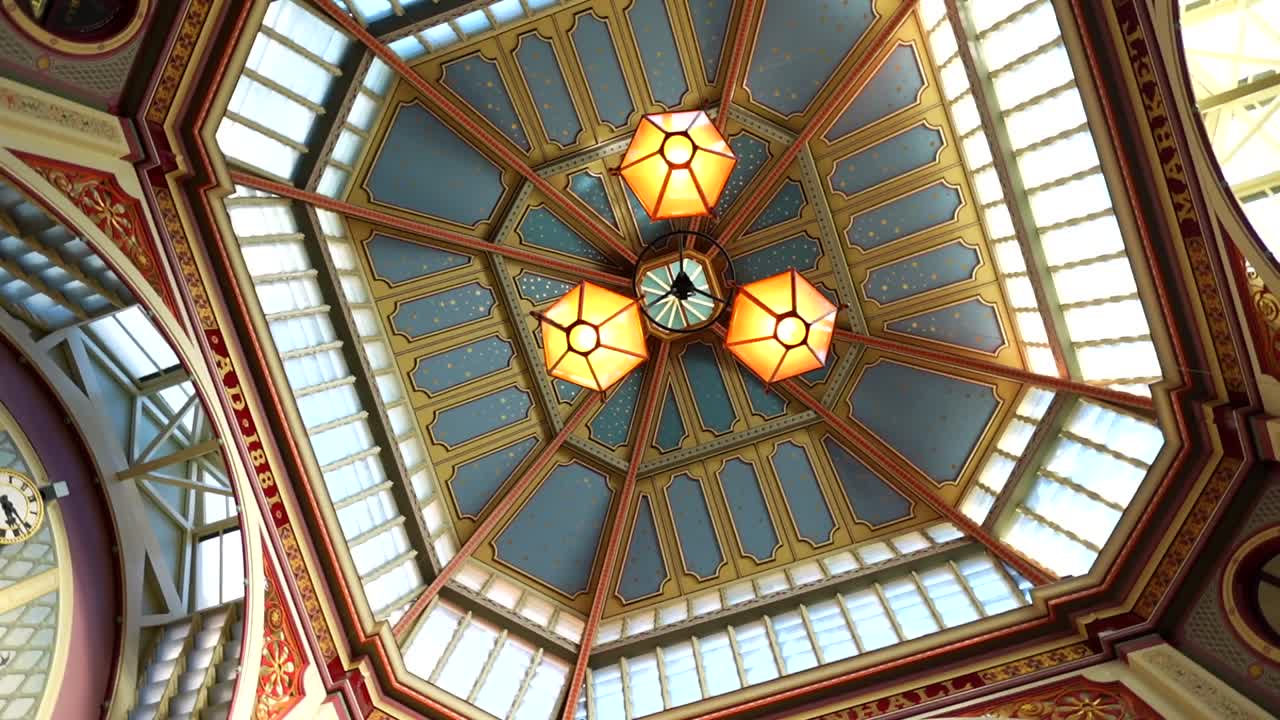 Three warm glowing lamps on the ornate ceiling of historic Leadenhall Market in London