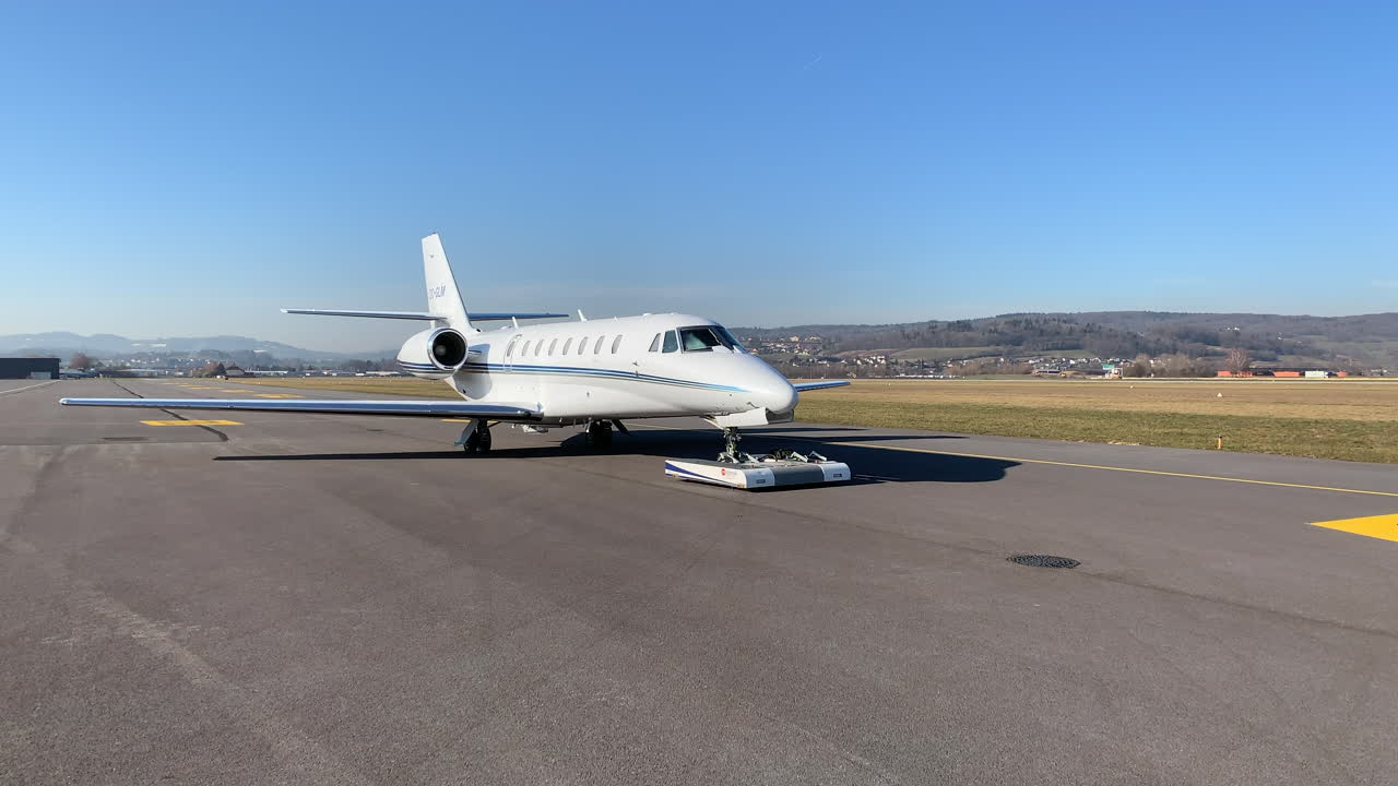 Executive private jet towing with robotic system on airport apron.