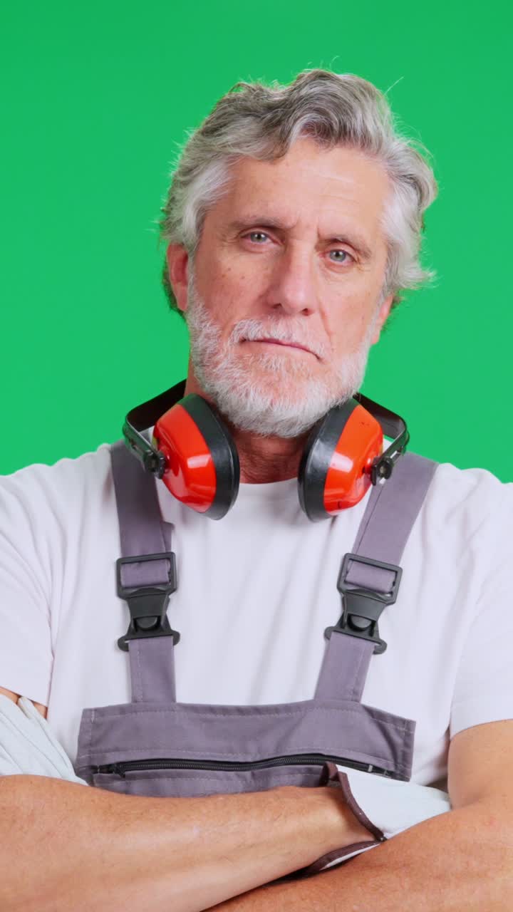 Seriøs moden mand i arbejdstøj og høreværn på greenscreen