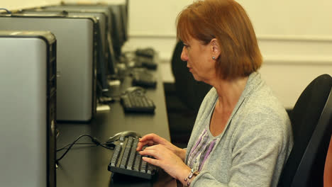 mature student working with a computer sitting in computer class