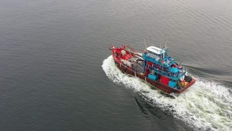 pescador en el mar para pescar por la mañana, drones aéreos vuelan alrededor de un barco de pesca tradicional con estela espumosa en la superficie del agua, lumut, manjung, perak, malasia