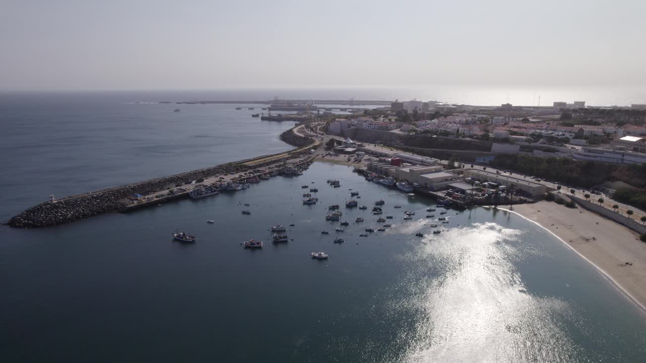 fotografía aérea en órbita del puerto de pesca de sines por la playa de vasco da gama, portugal