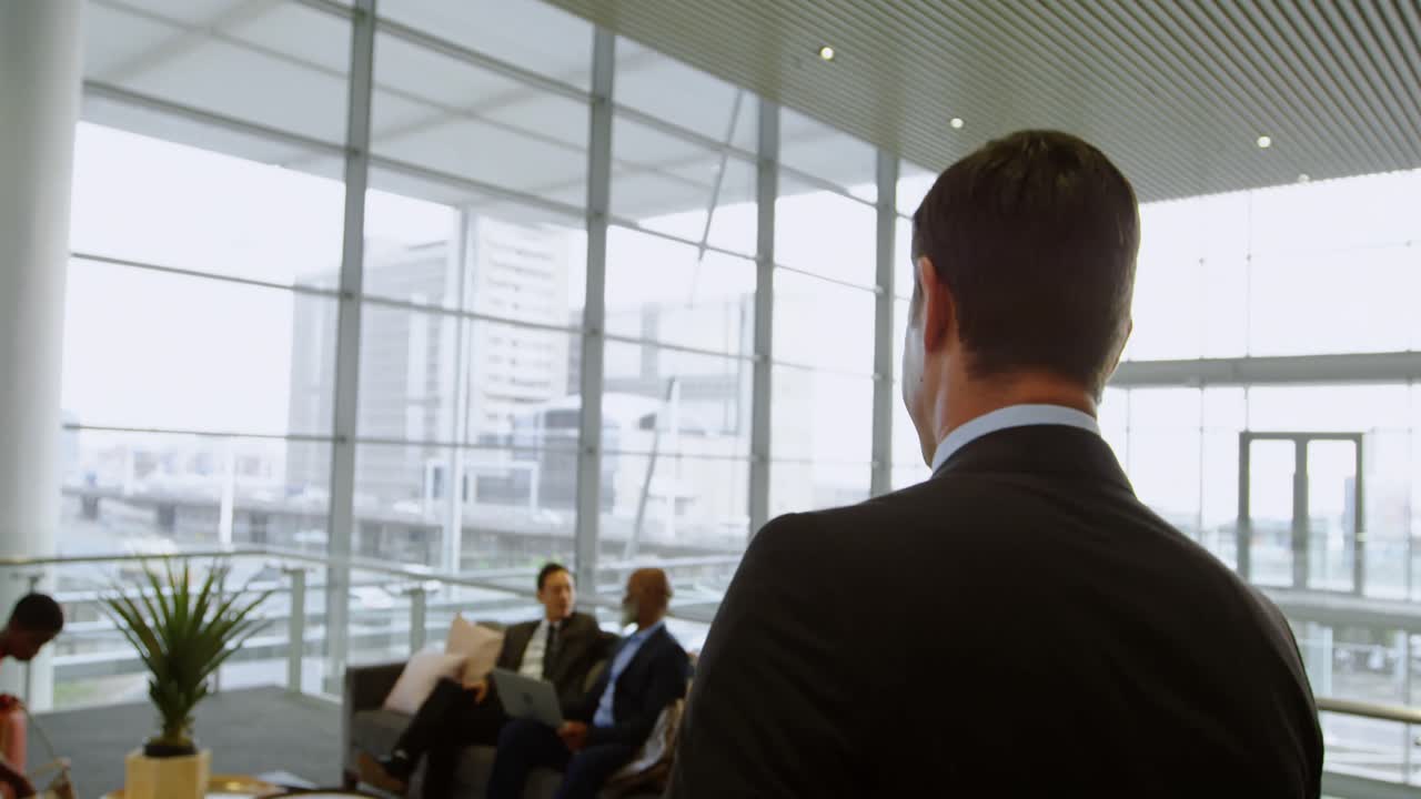 Uomo d'affari che cammina verso i suoi colleghi in ufficio 4k