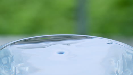 droplets of water sputtering and in a glass filled with water and creating ripples and waves