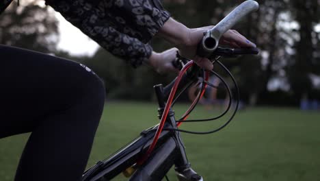 Female-hands-on-bicycle-in-the-park-medium-shot-slow-panning-shot