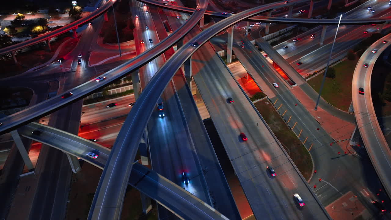 Viaduto rodoviário deslumbrante com tráfego intenso. Carros passando pelas rodovias e cavaletes à noite. Vista aérea